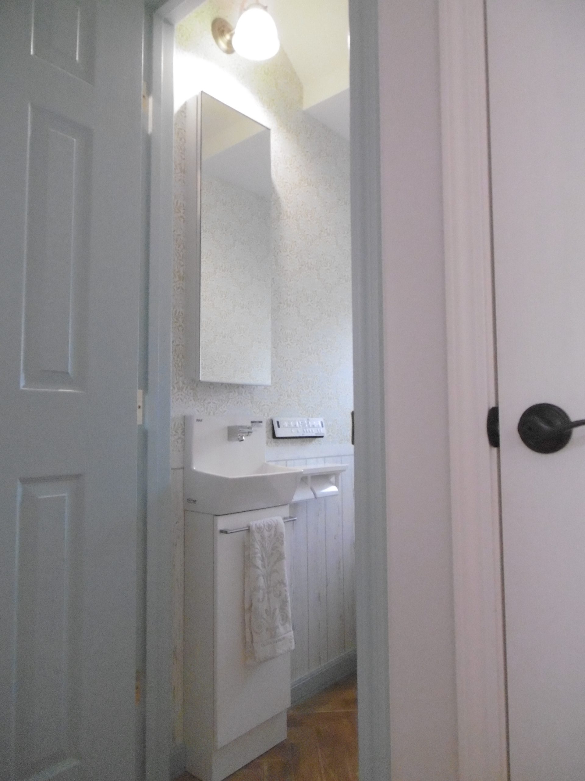 １Ｆトイレの上部収納付手洗い器。扉はブルーグレー色のペイント。
